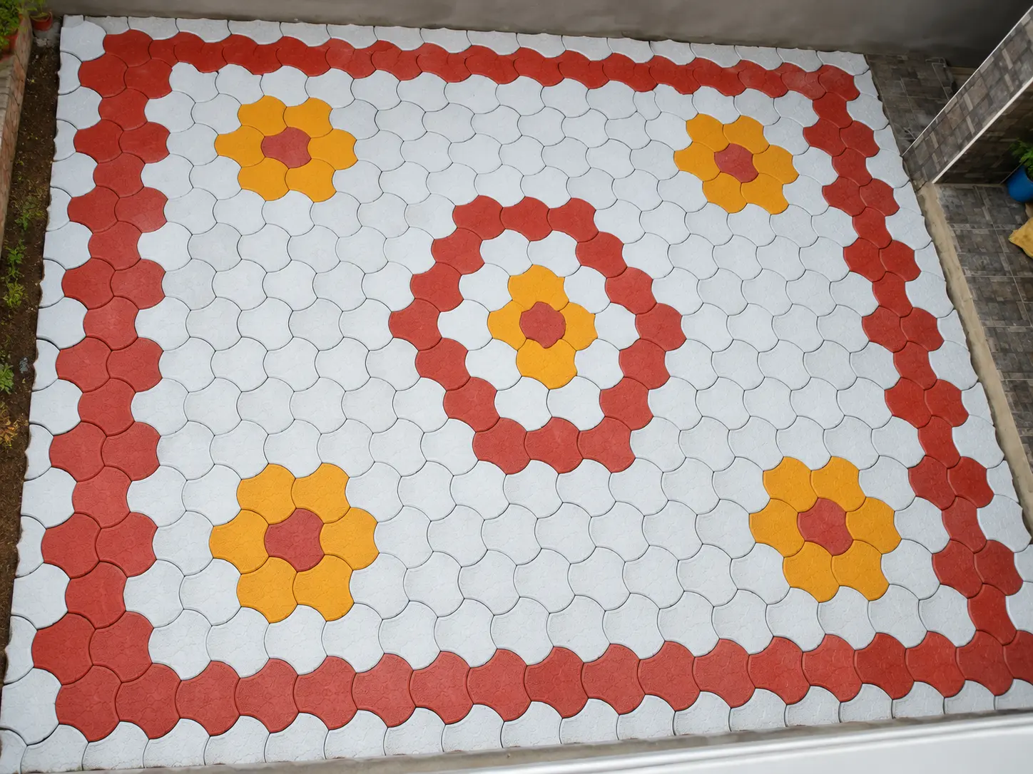 Overhead view of flower pattern pavers with red border and yellow flower medallions